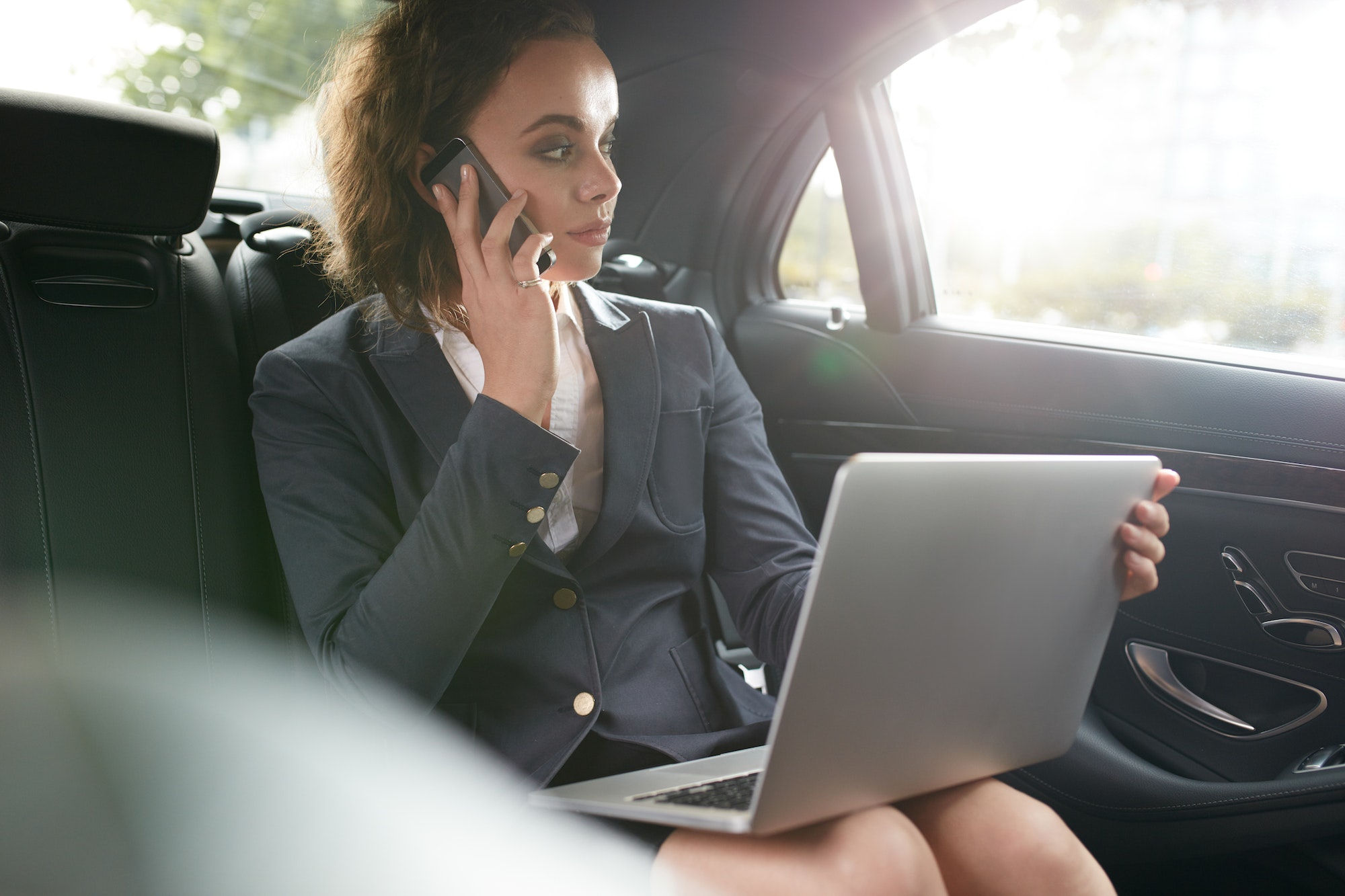 Female executive travelling to work in luxury car